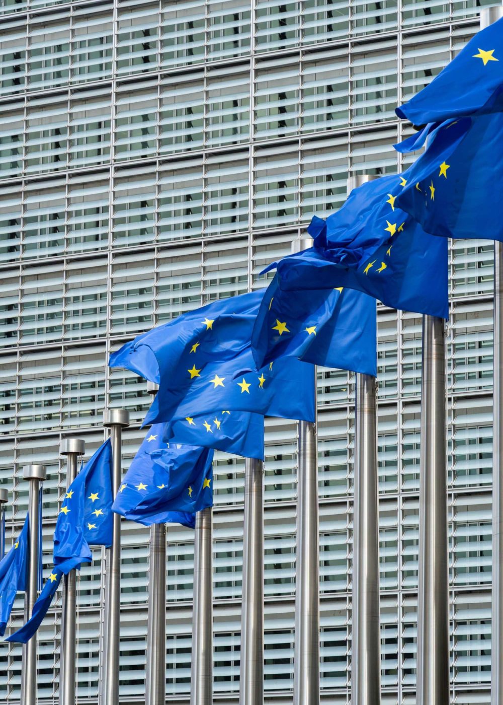 Row of European Union Blue Flags and Berlaymont Building, Headquarters of the European Commission. City of Brussels, Belgium
